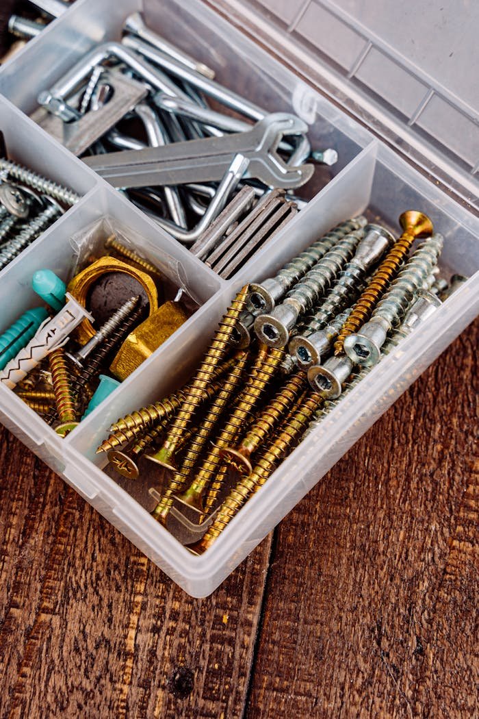 Close-up view of a toolbox containing assorted screws, wrenches, and tools on a wooden surface.
